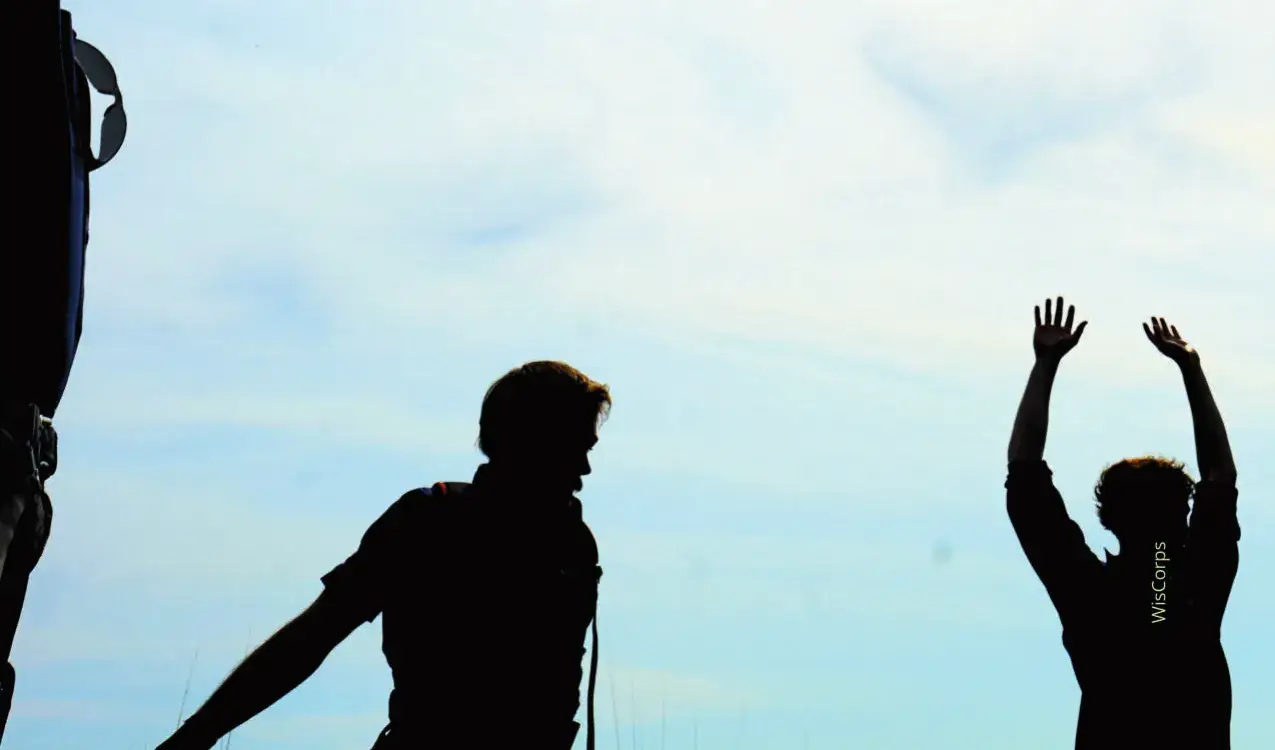 Silhouettes of crew members cheering on a ridge
